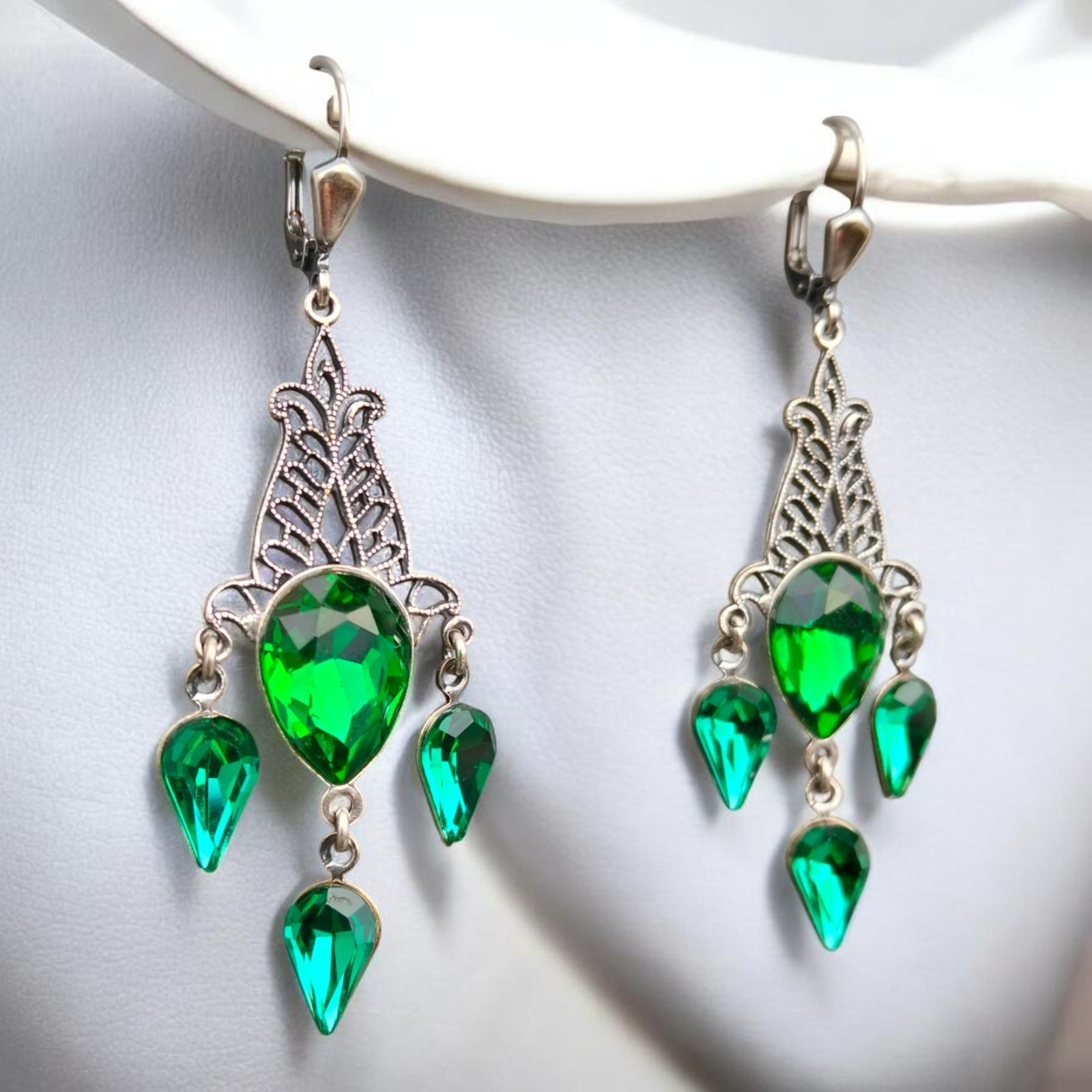 Grüne Chandelier-Ohrringe mit Kristallglas in Emerald, versilbert, an einer weißen Büste