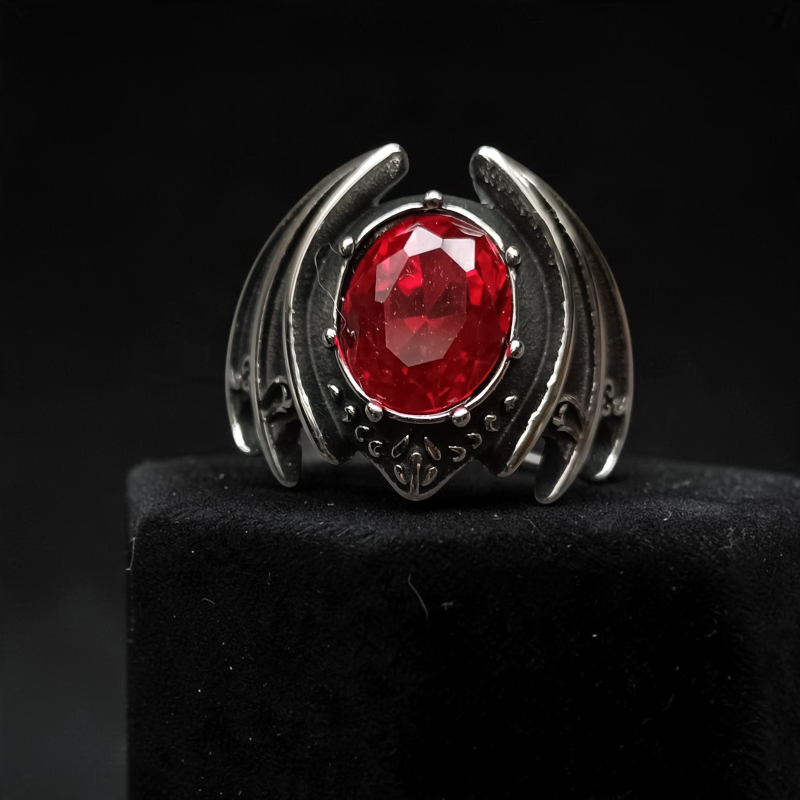 Fledermausring aus Edelstahl, Vorderansicht mit ovalem rotem Stein und gespannten Flügeln