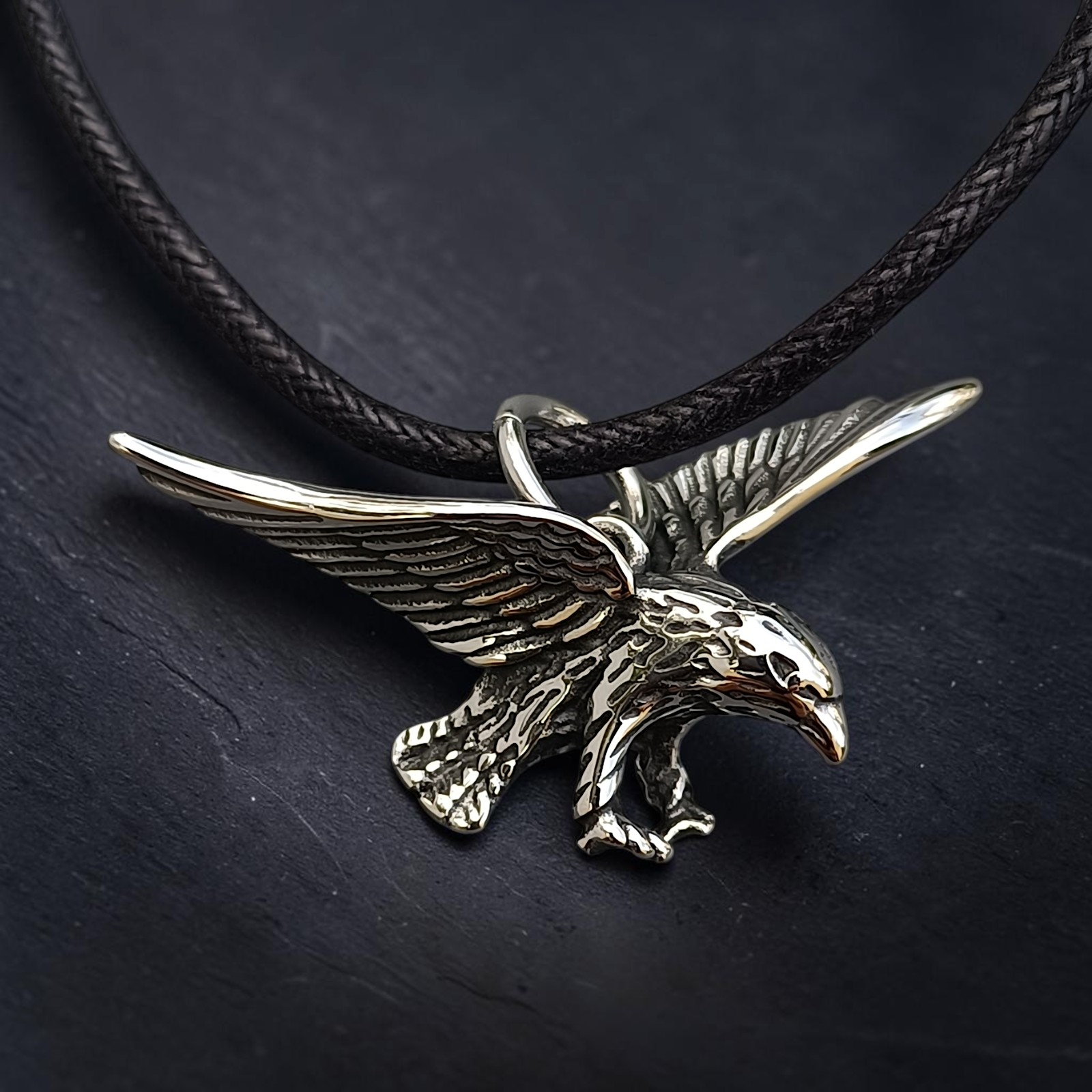 Anhänger fliegender Adler aus Edelstahl am schwarzen Band auf Schiefer