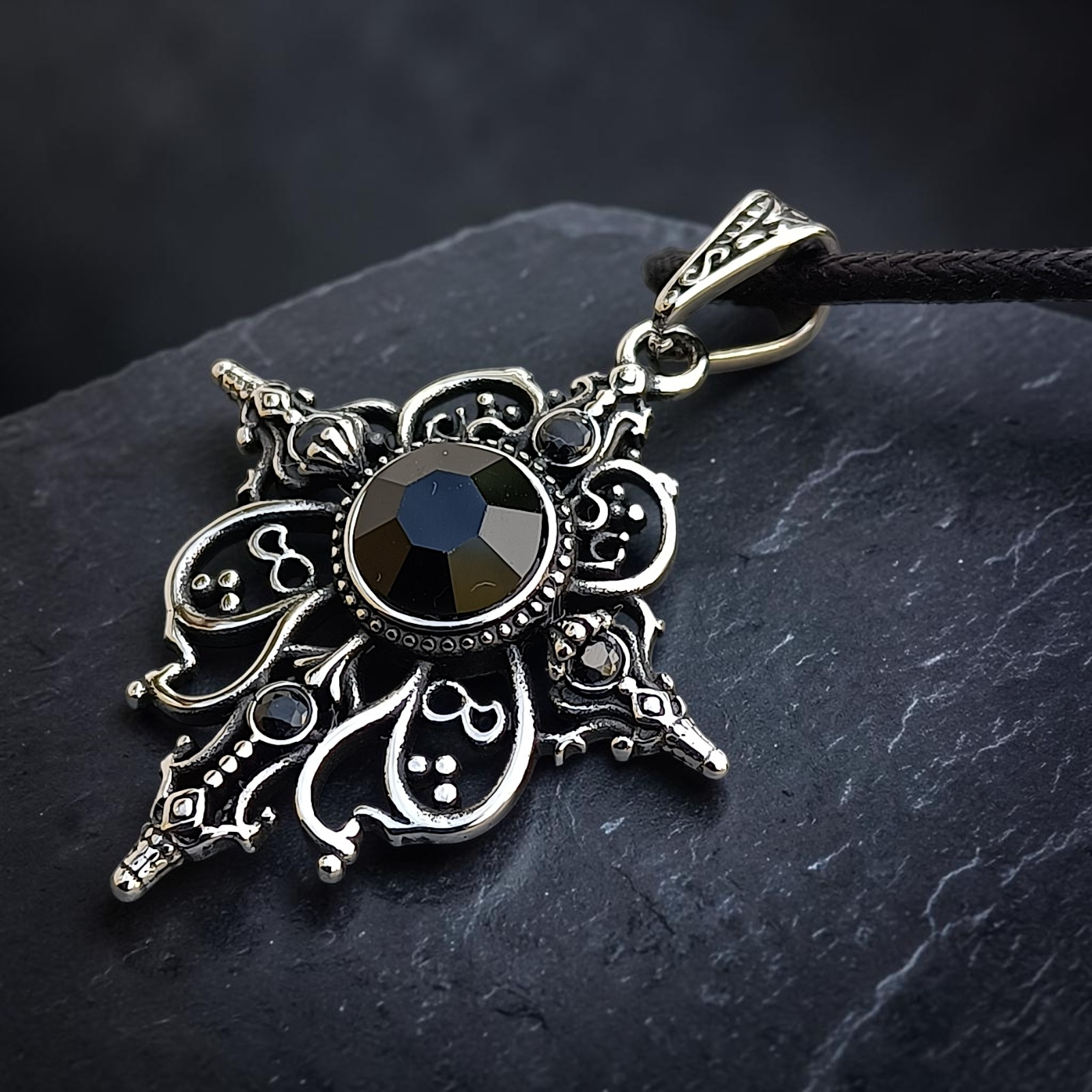 Ornamentanhänger Arwen mit schwarzem Zirkonia liegend auf dunklem Stein