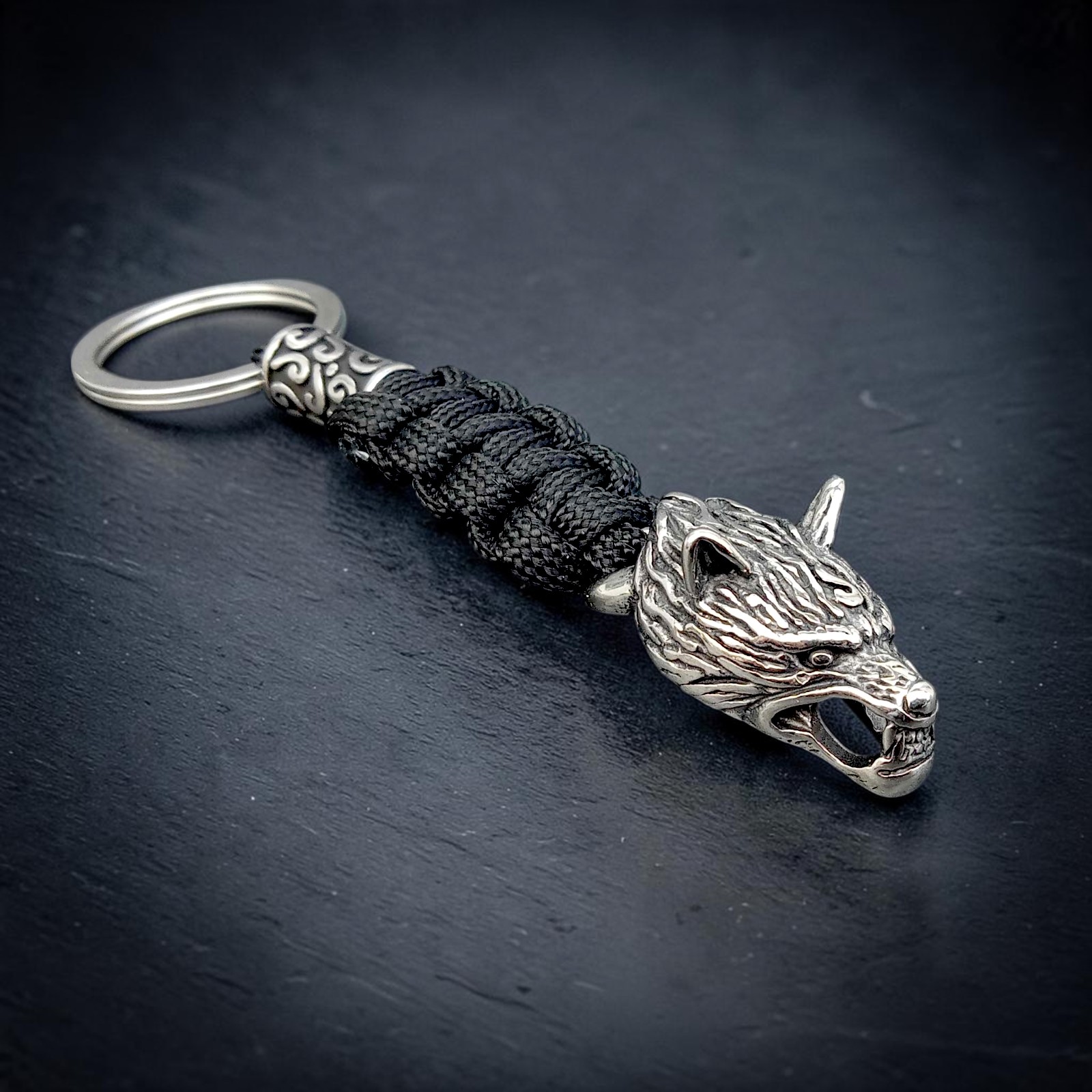 Schlüsselanhänger mit Wolfskopf aus Edelstahl und schwarzem Paracord-Geflecht