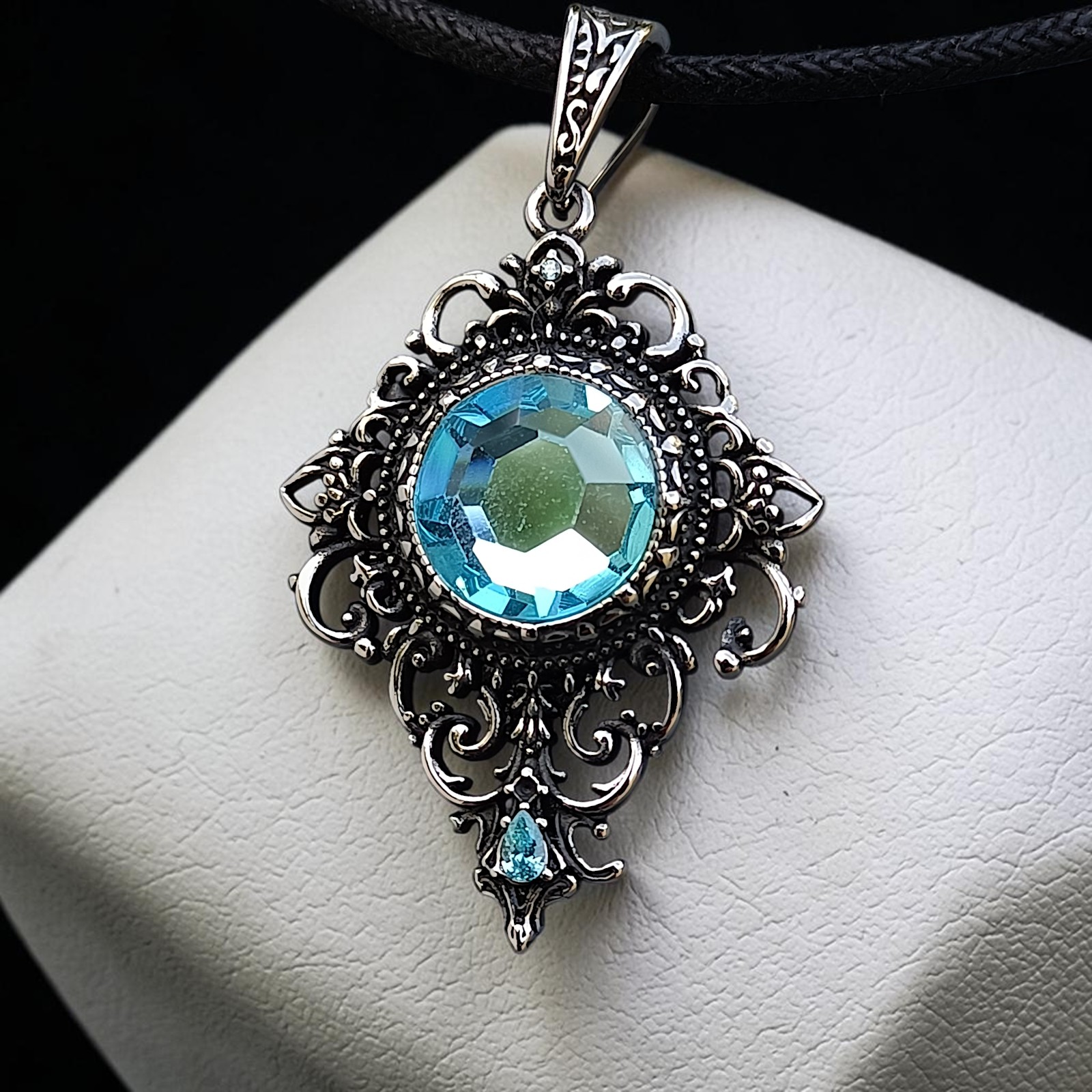 Ornamentanhänger Rhea mit hellblauem Zirkonia auf weißem Kissen