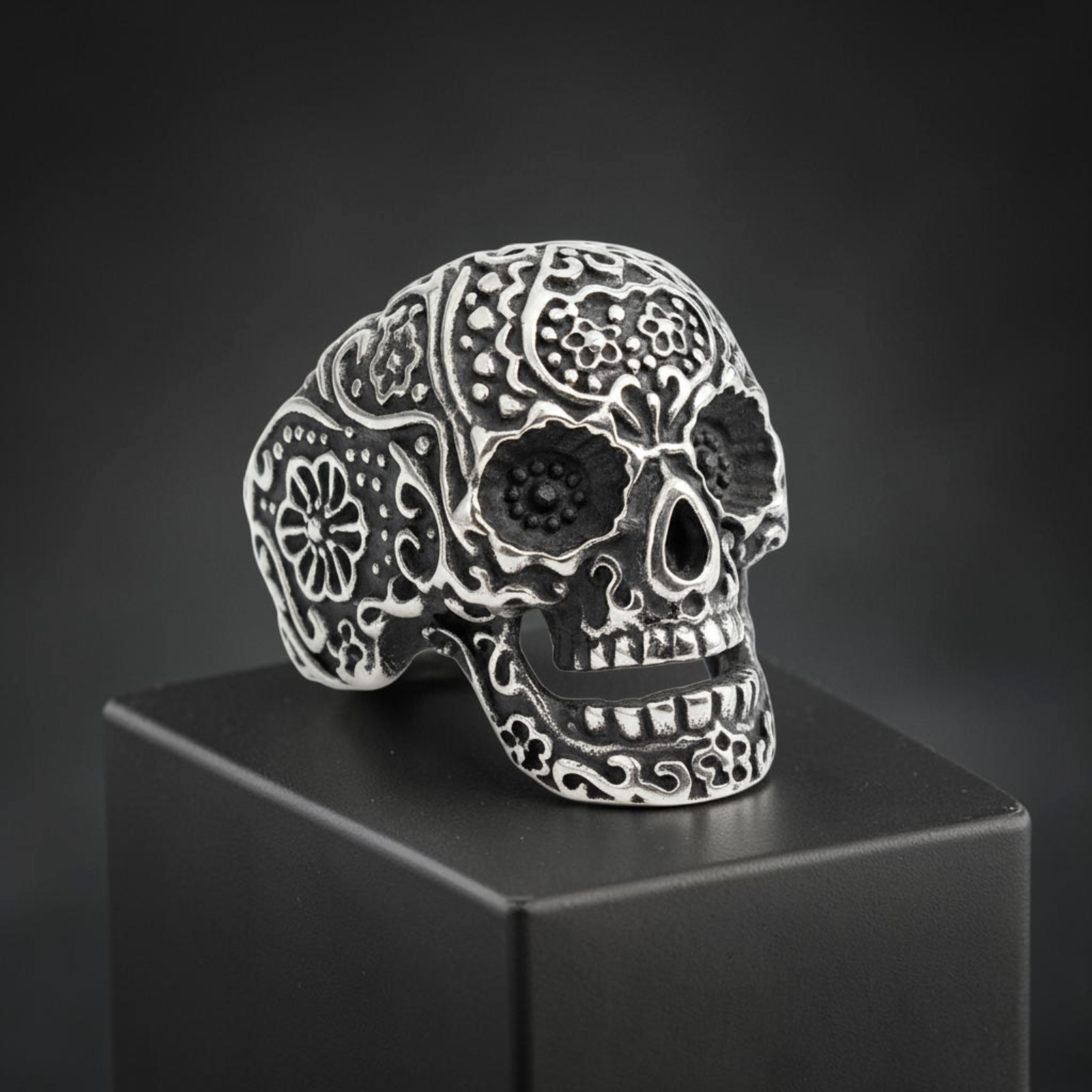 Totenkopfring aus Edelstahl im Sugar-Skull-Stil mit Blumenornamenten auf schwarzem Sockel