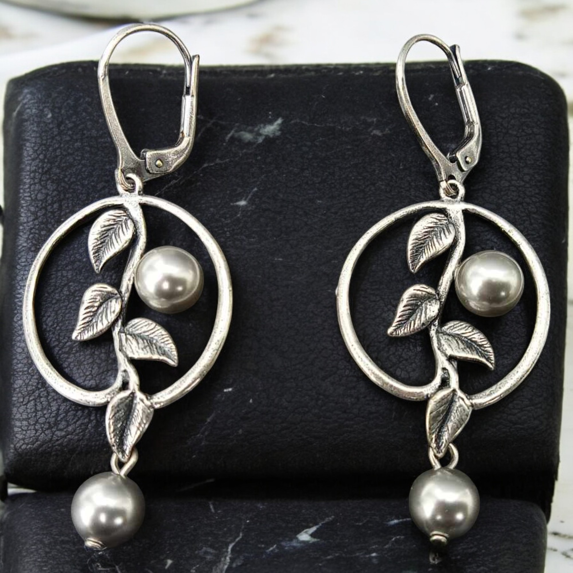 Perlenohrringe mit ziselierten Blättern im Ring, eine Perle innen, eine frei hängend, in Light Grey