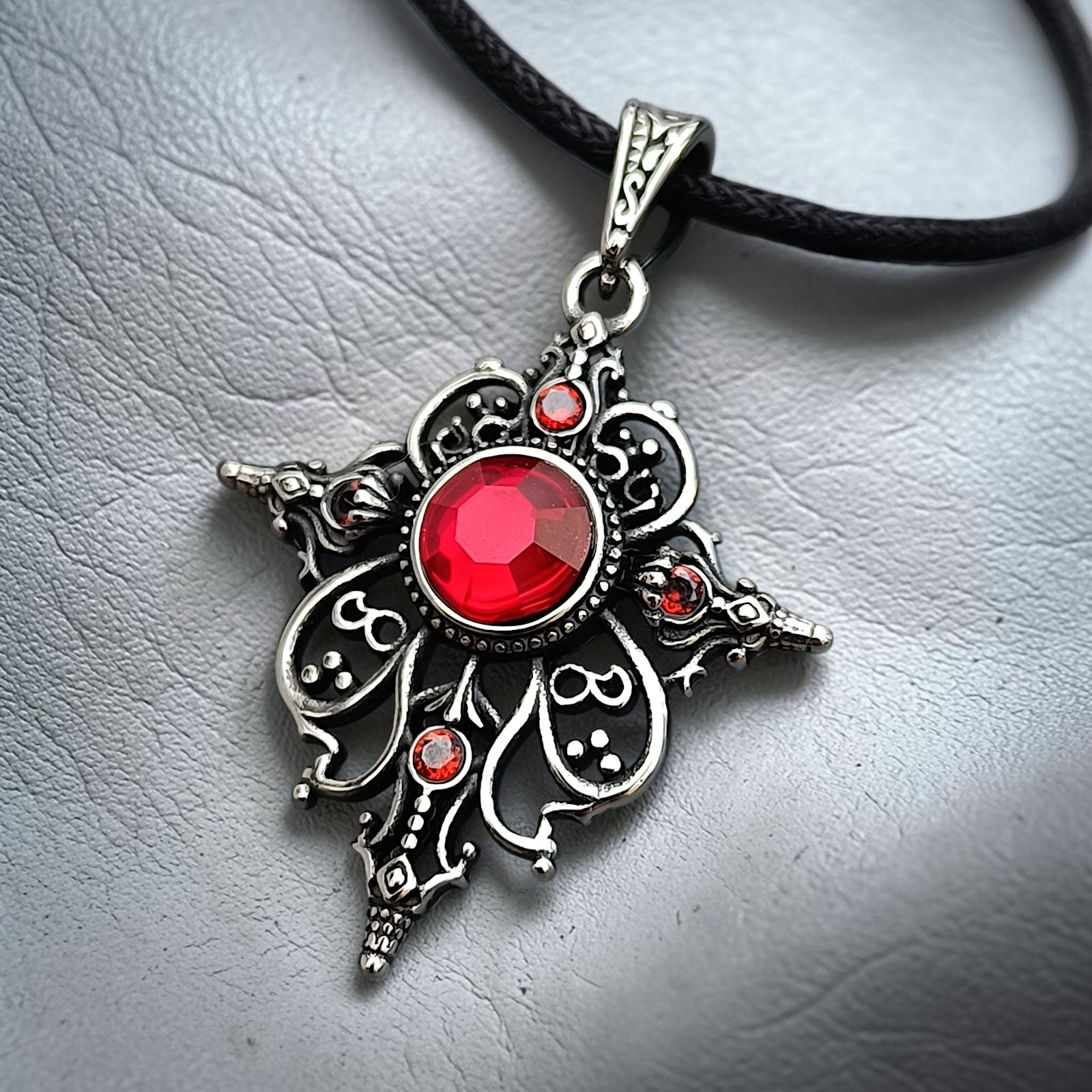 Ornamentanhänger Arwen mit rotem Zirkonia schräg vor hellem Hintergrund