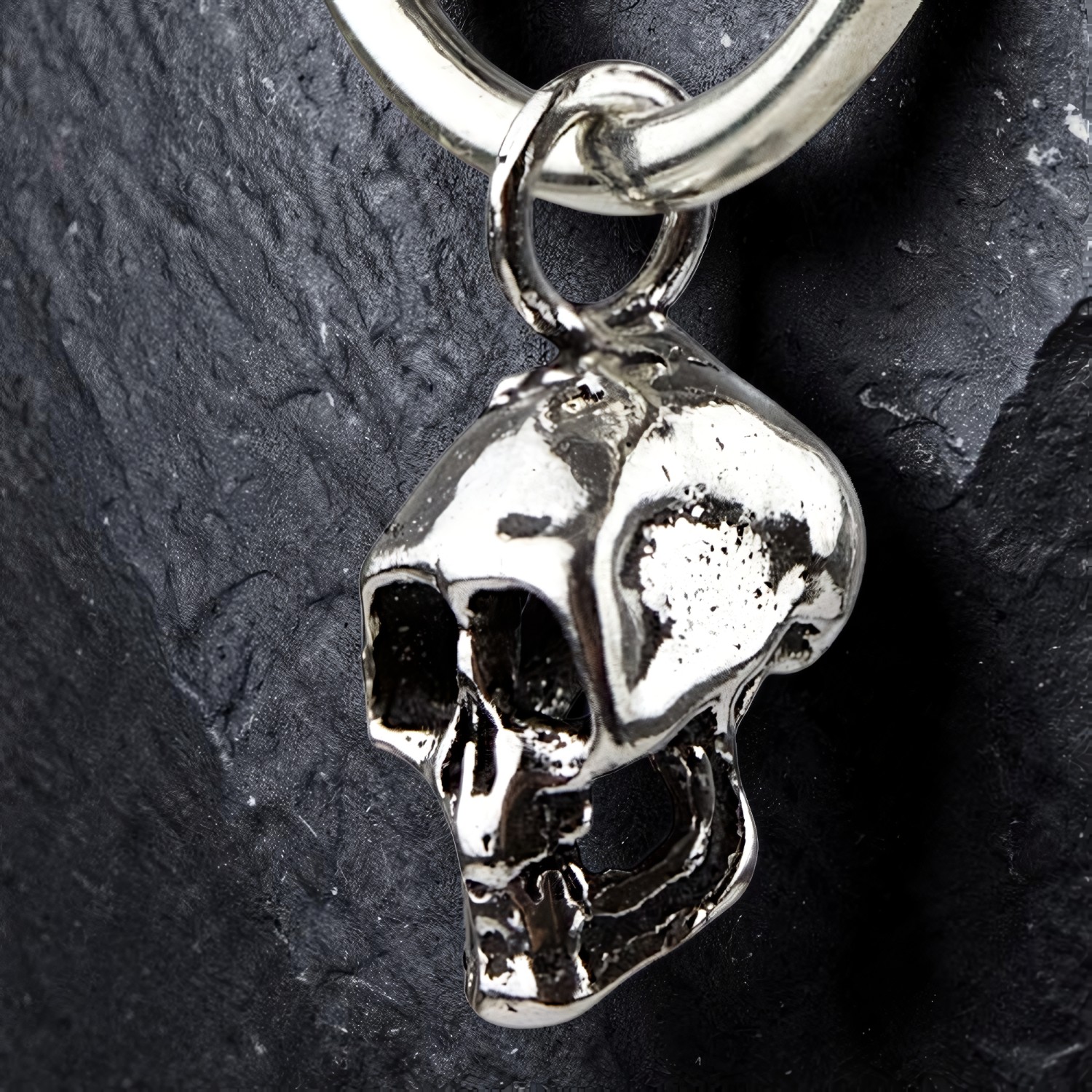 Totenkopf-Anhänger einer Silbercreole in Nahaufnahme