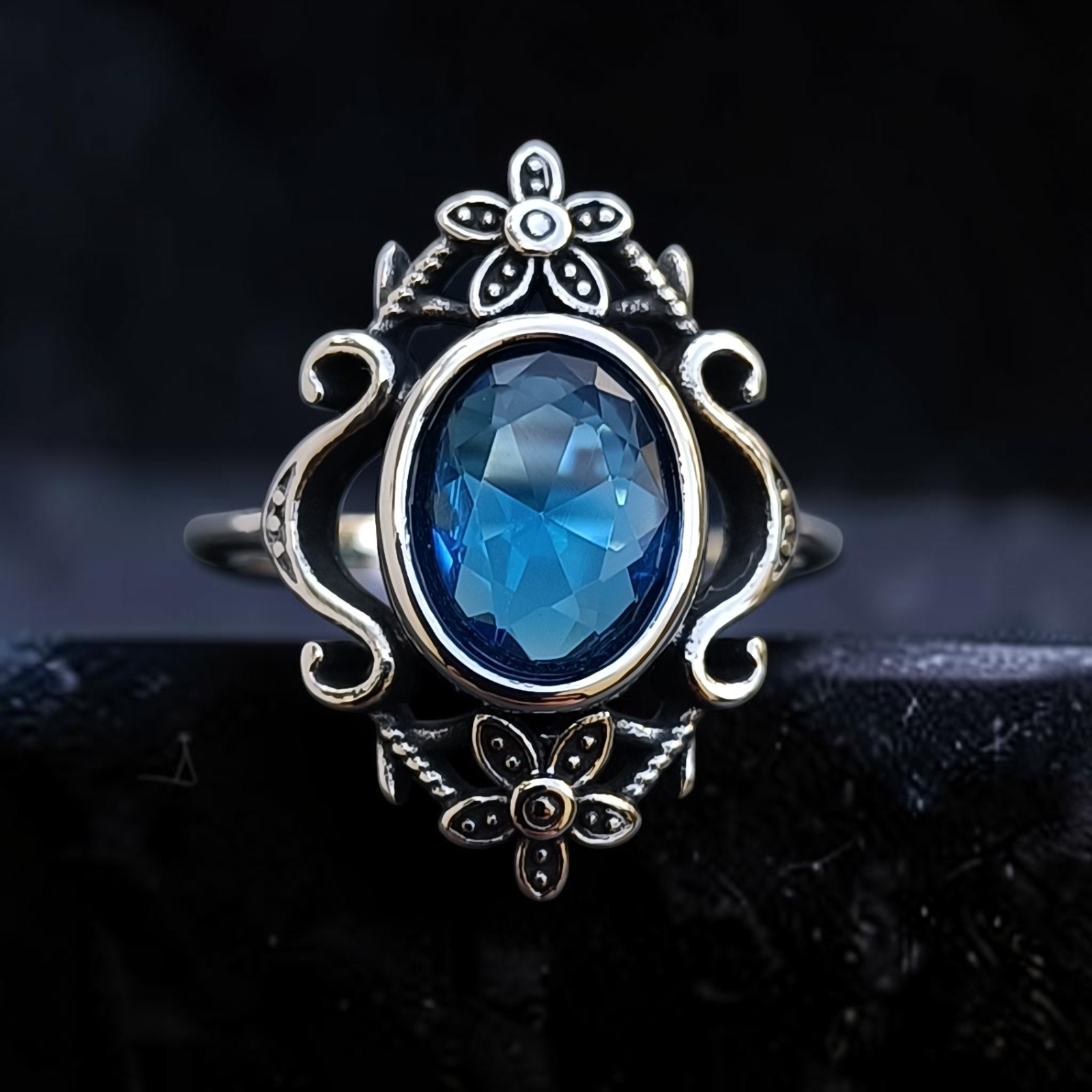 Ring Blue Topaz Flowers aus Edelstahl mit ovalem blauem Zirkonia zwischen Blüten und Schnörkeln