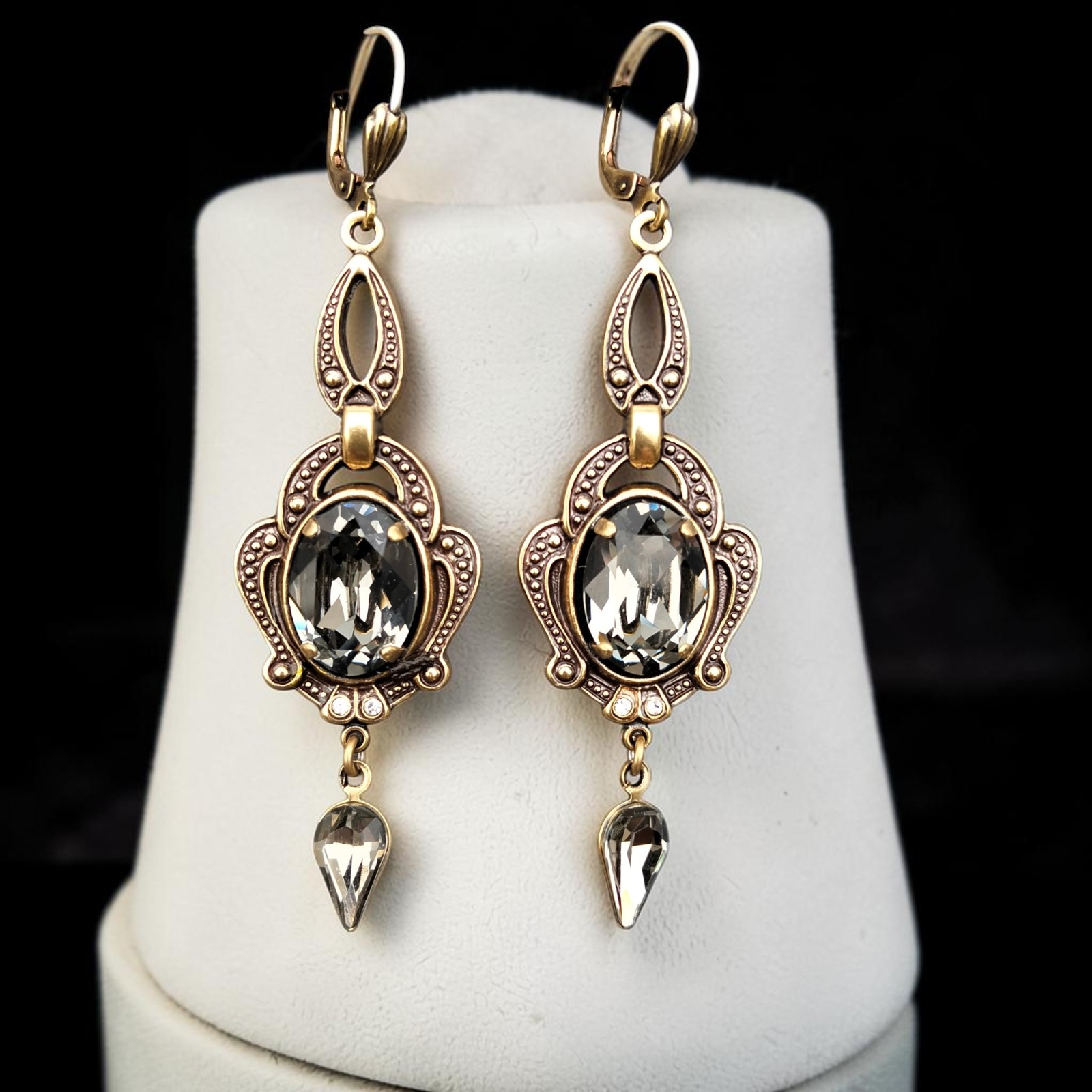 Goldfarbene Vintage-Ohrhänger mit rauchgrauem Kristallglas in Black Diamond auf einer weißen Büste
