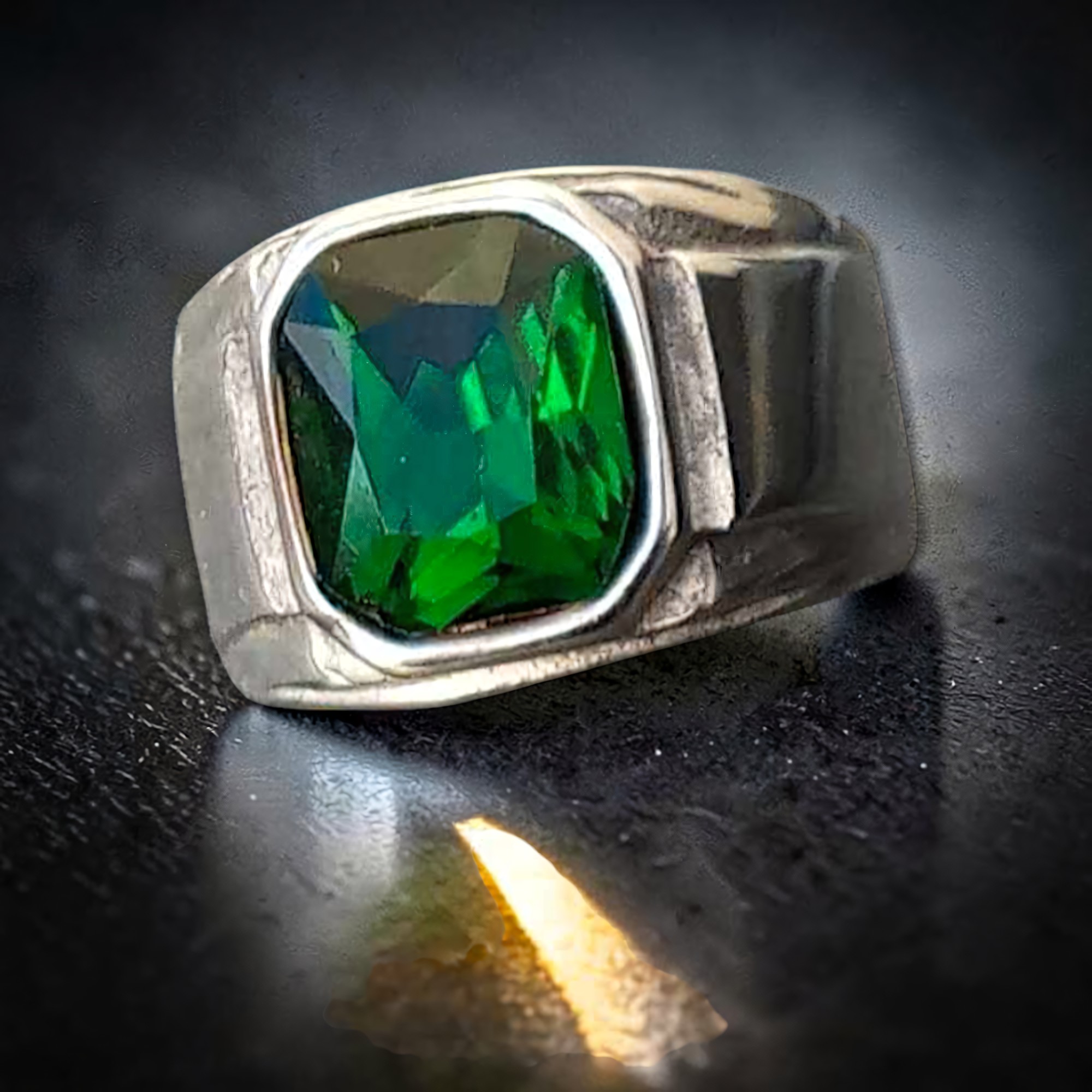 Grüner Zirkonia-Ring aus Edelstahl mit Lichtreflex auf dunklem Untergrund