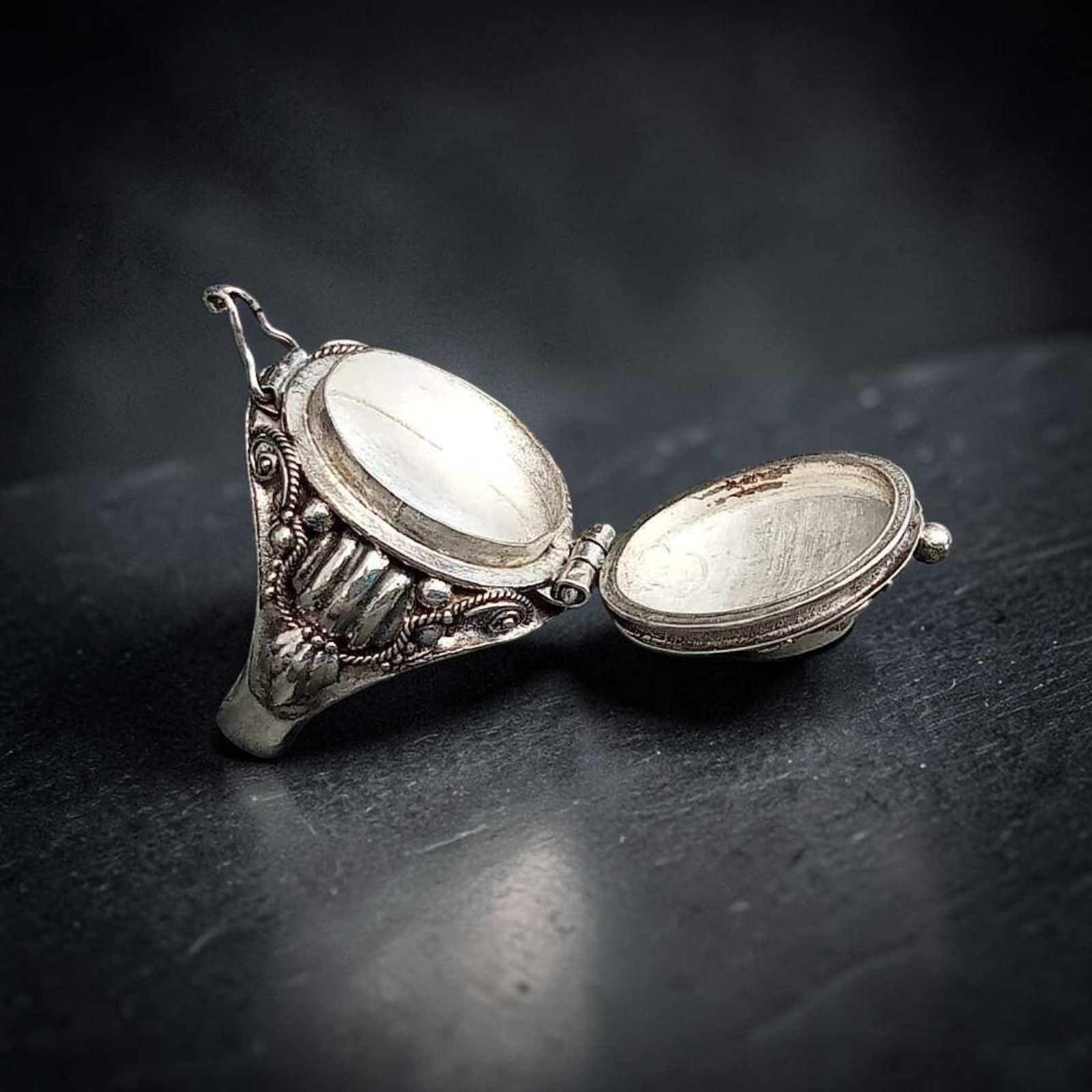 Geöffneter Giftring aus Silber mit hochgeklapptem Deckel und leerem Fach, seitlich