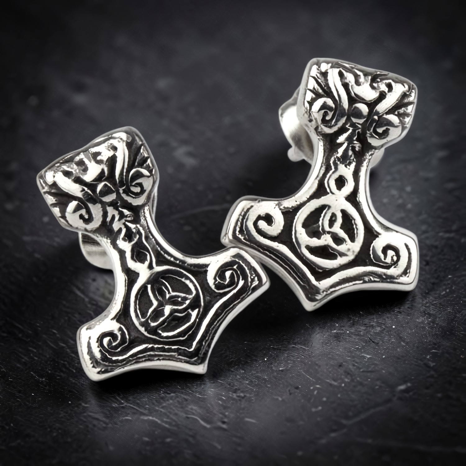 Paar Ohrstecker Thors Hammer aus Edelstahl mit Tierkopf und Knotenmotiv auf dunklem Schiefer