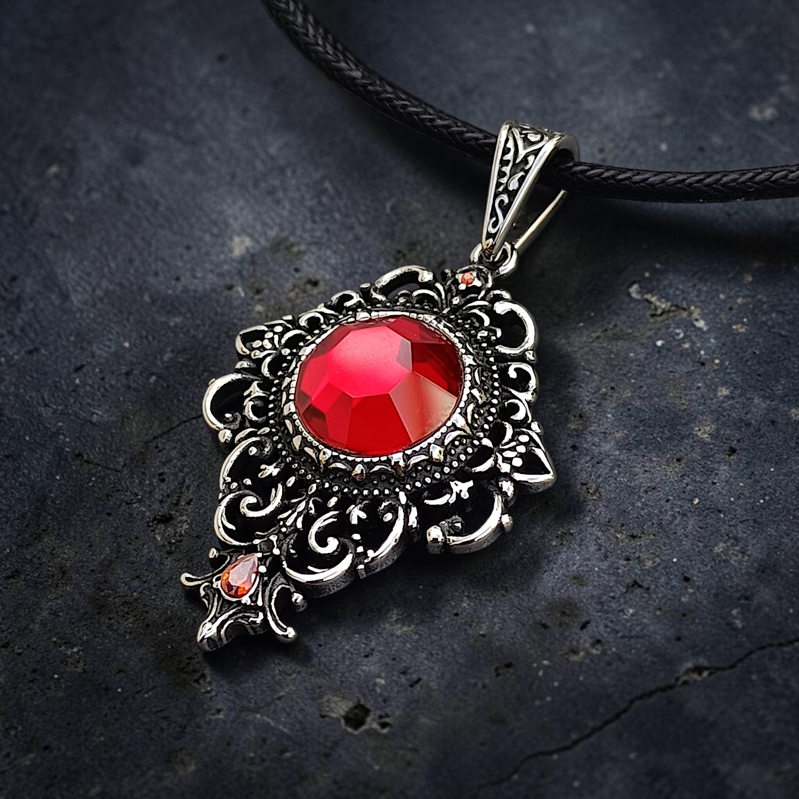 Ornamentanhänger Rhea mit rotem Zirkonia auf dunklem Stein