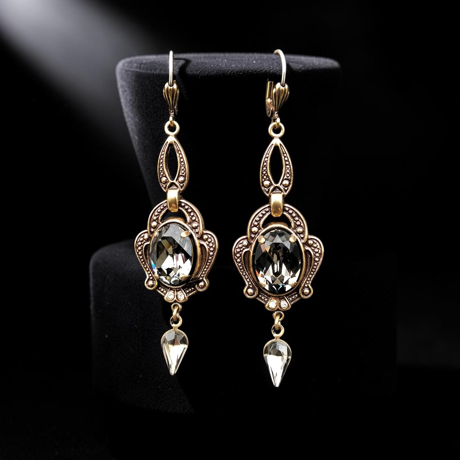 Ohrhänger in Black Diamond vor schwarzem Hintergrund mit antikisierter, goldfarbener Ornamentfassung