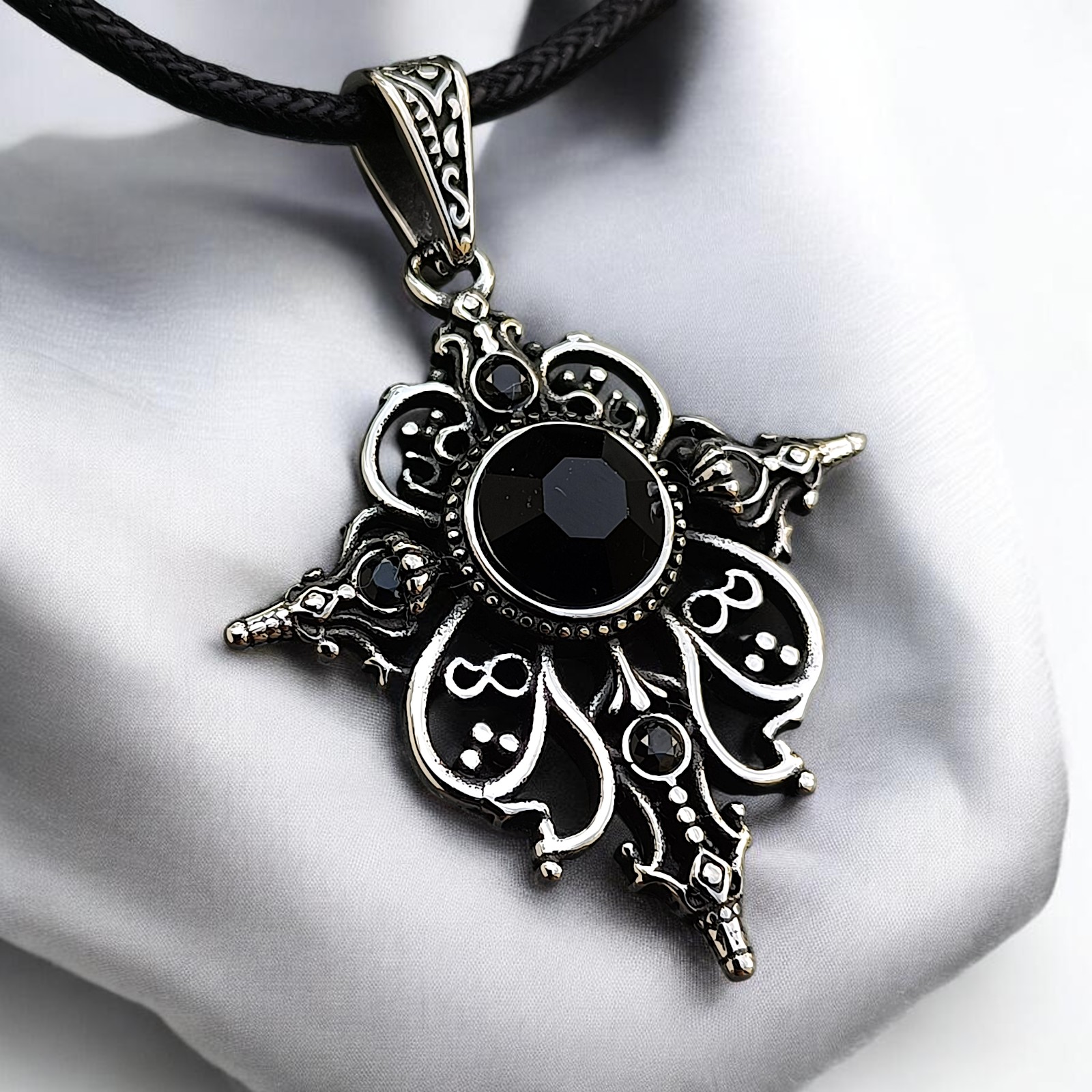 Ornamentanhänger Arwen mit schwarzem Zirkonia schräg auf weißem Stoff