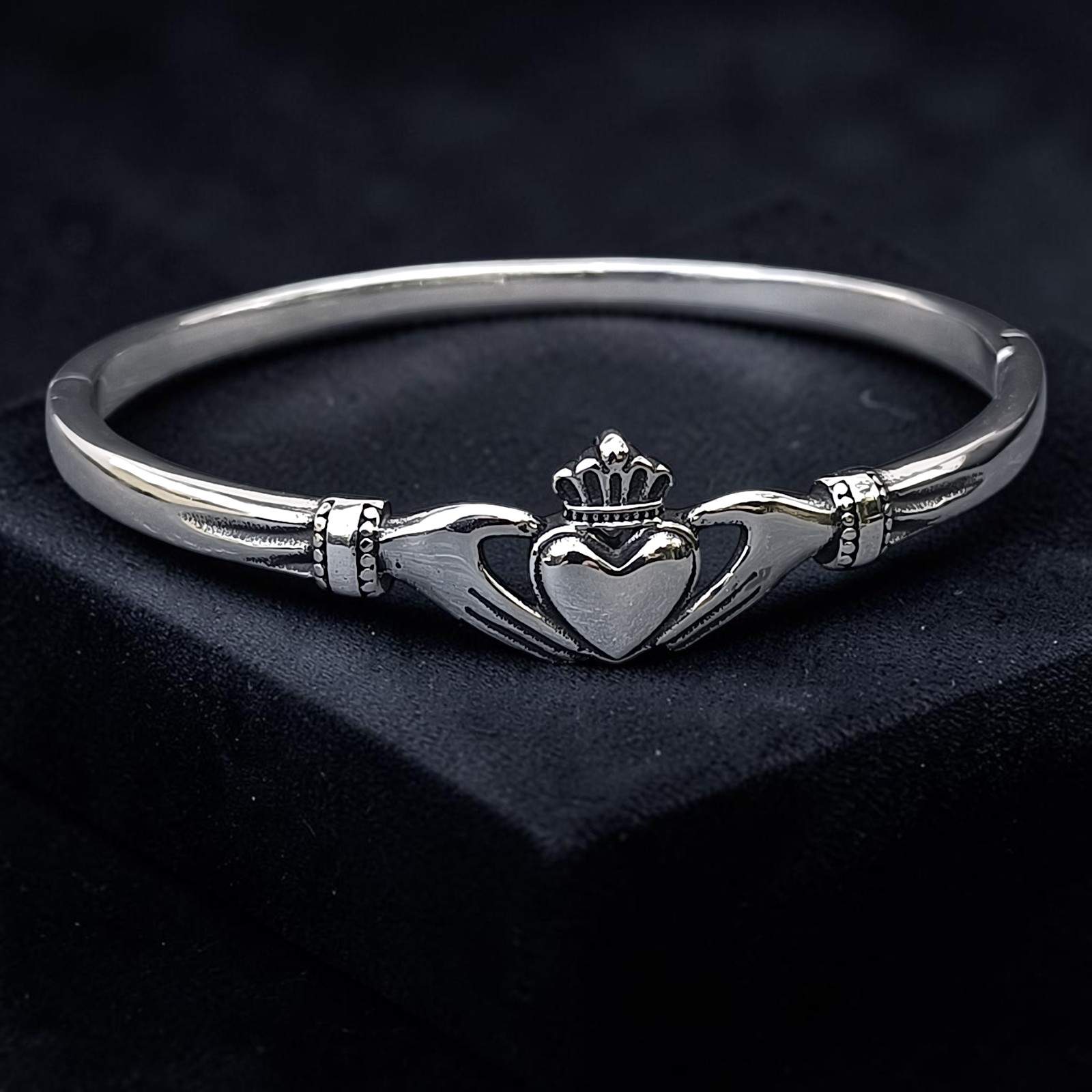 Armreif Claddagh aus Edelstahl mit Händen, Herz und Krone auf schwarzem Untergrund