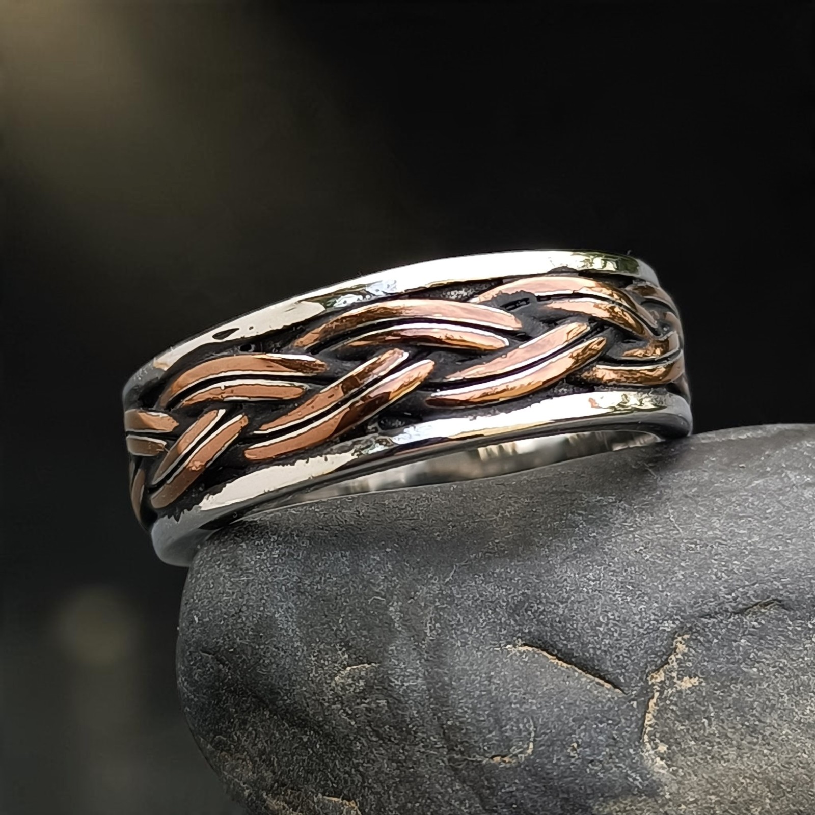 Spielring aus Edelstahl mit bronzefarbenem keltischem Flechtband auf einem dunklen Stein