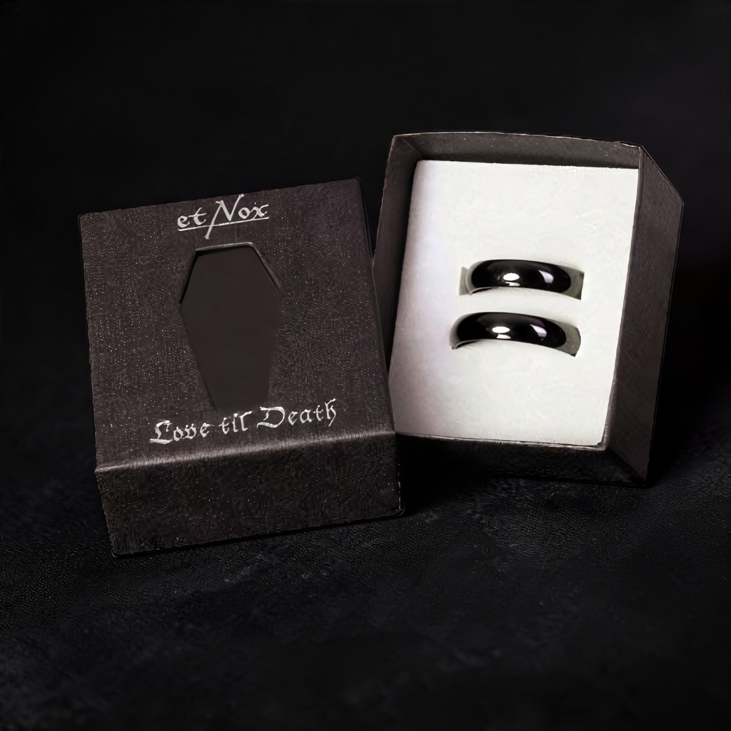Geöffnete Geschenkbox mit zwei schwarzen Ringen, im Deckel ein ausgestanzter Sarg
