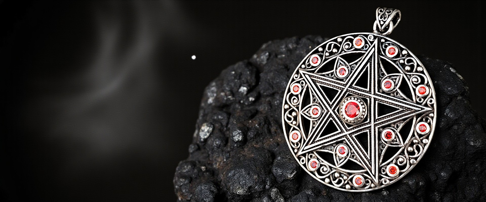 Pentagramm-Pendant mit roten Steinen auf rauem Stein