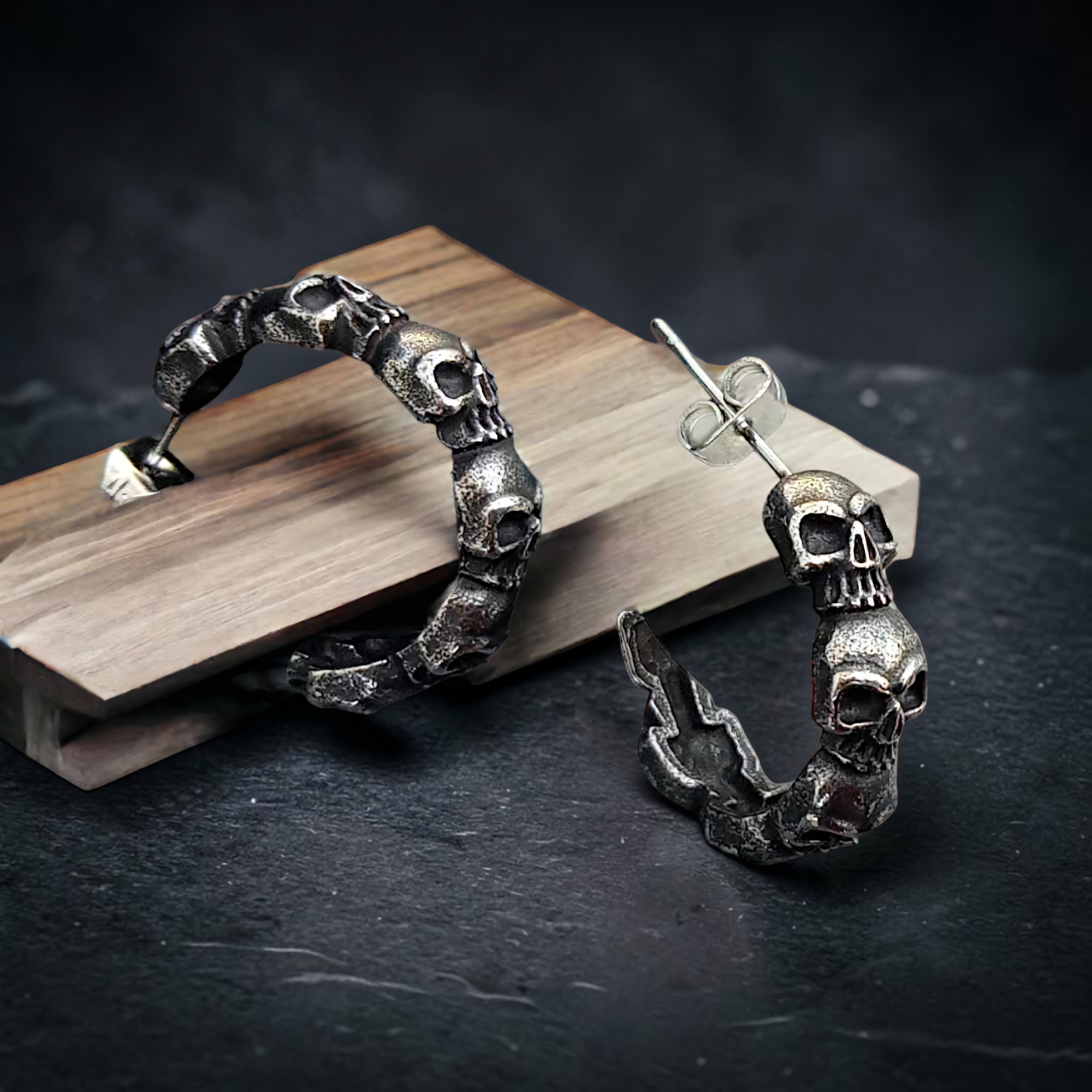Paar Totenkopf-Creolen im Antik-Look auf einem Holzklotz