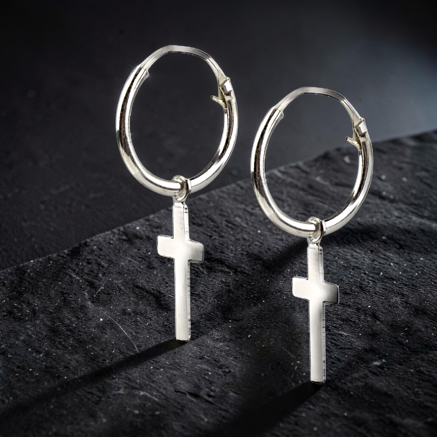 Silbercreolen mit kleinem Kreuz-Anhänger auf dunklem Stein