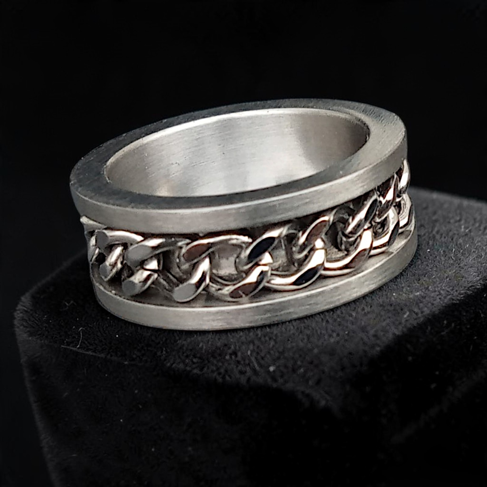 Partnerring aus Edelstahl mit eingelassener Kette auf schwarzem Sockel