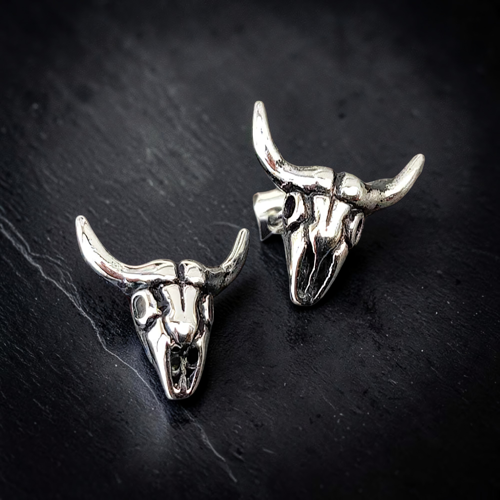 Paar Edelstahl-Ohrstecker in Form eines Longhorn-Schädels auf Schiefer