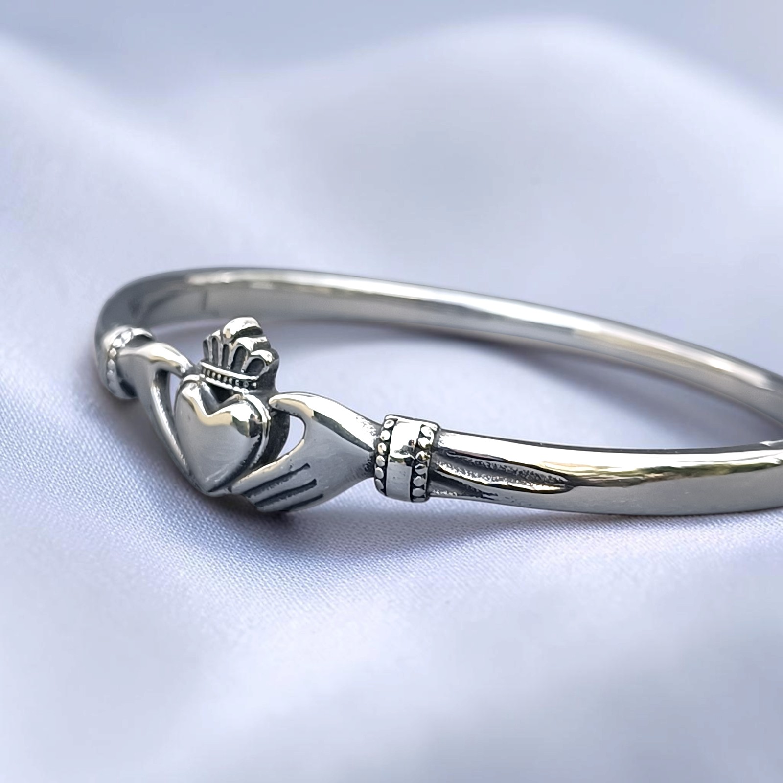 Schmaler Edelstahl-Armreif mit Claddagh-Motiv auf hellem Satin